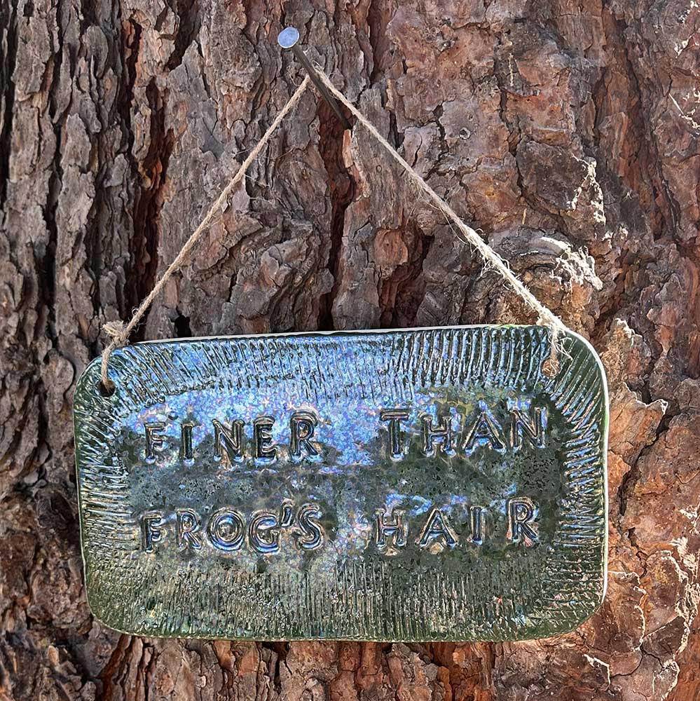"finer than frog's hair" ceramic hanging sign in june bug with texture border