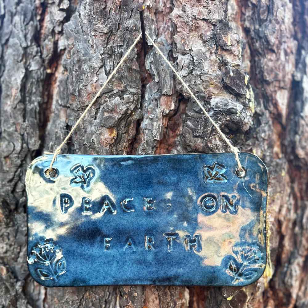 "peace on earth" hanging ceramic sign in sapphire with dove and flower stamps