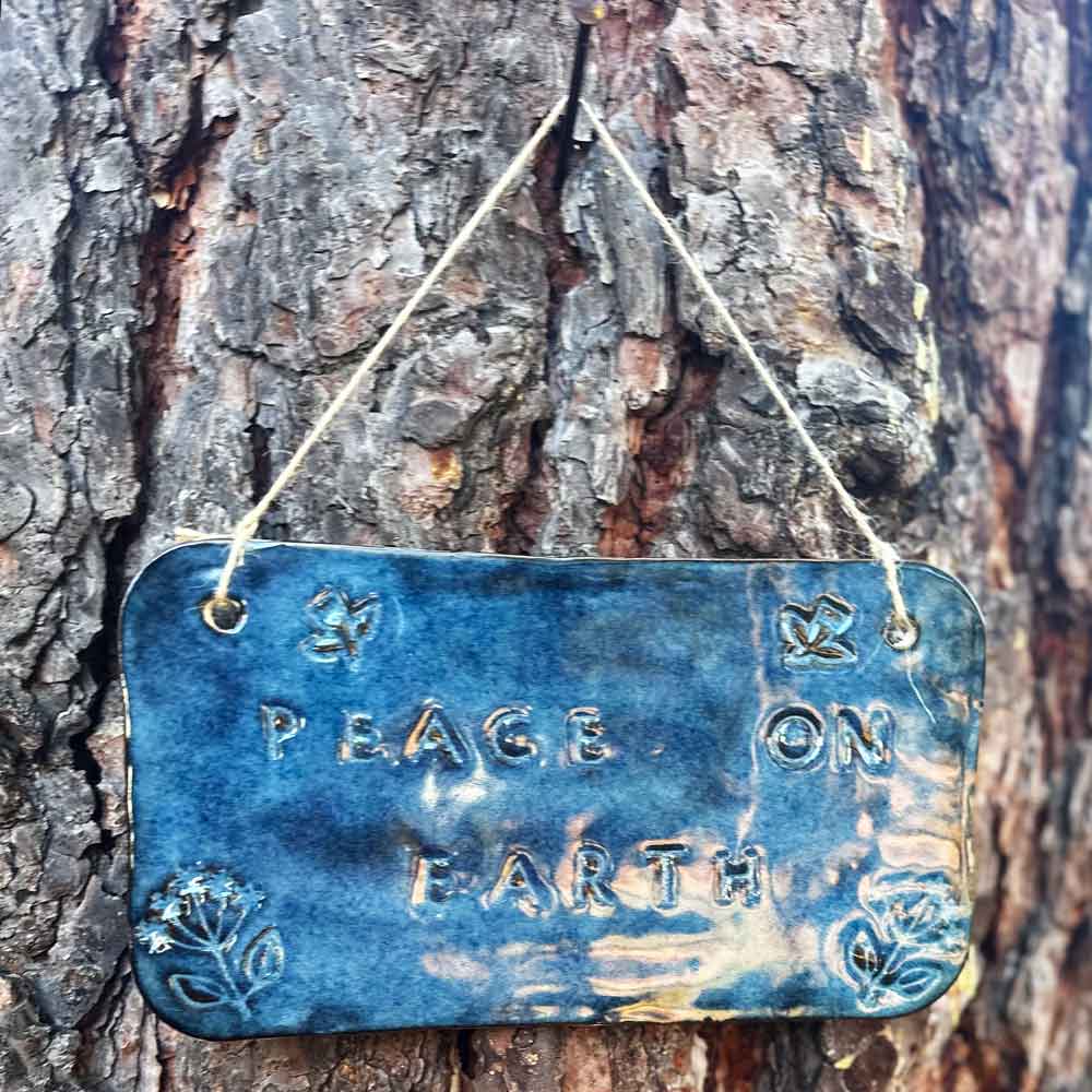 "peace on earth" hanging ceramic sign in sapphire with dove and flower stamps