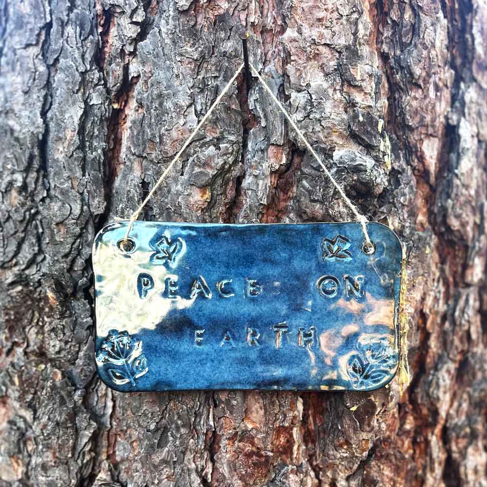 "peace on earth" hanging ceramic sign in sapphire with dove and flower stamps