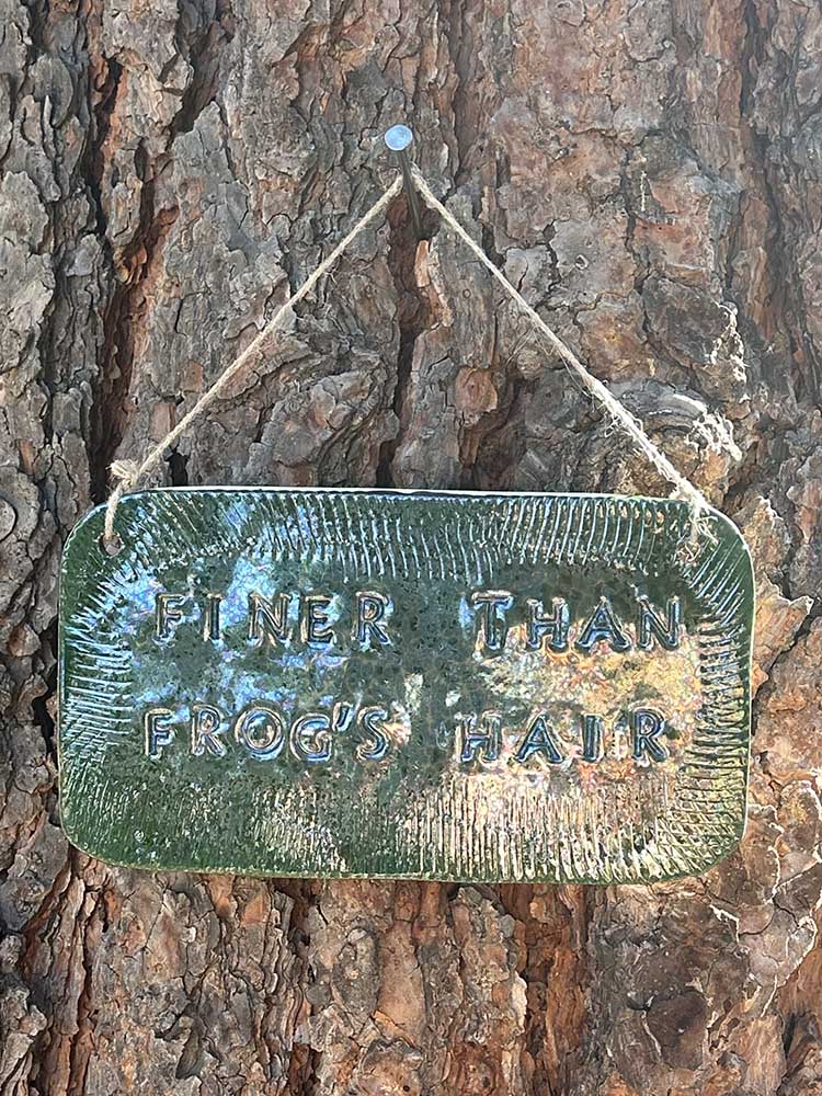 "finer than frog's hair" ceramic hanging sign in june bug with texture border